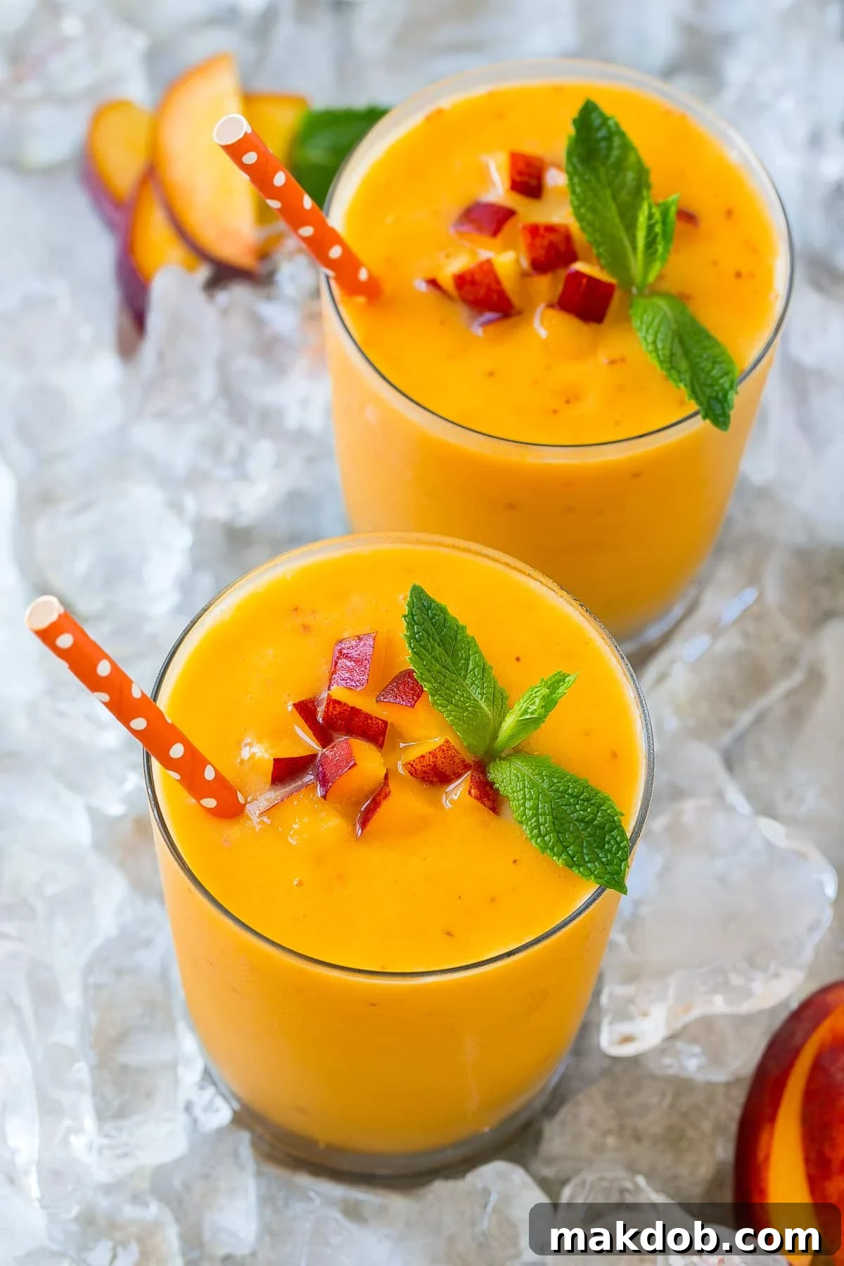 Two peach smoothies with straws in them.