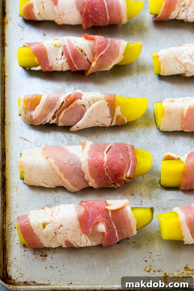 Pickle spears wrapped in bacon on a sheet pan.
