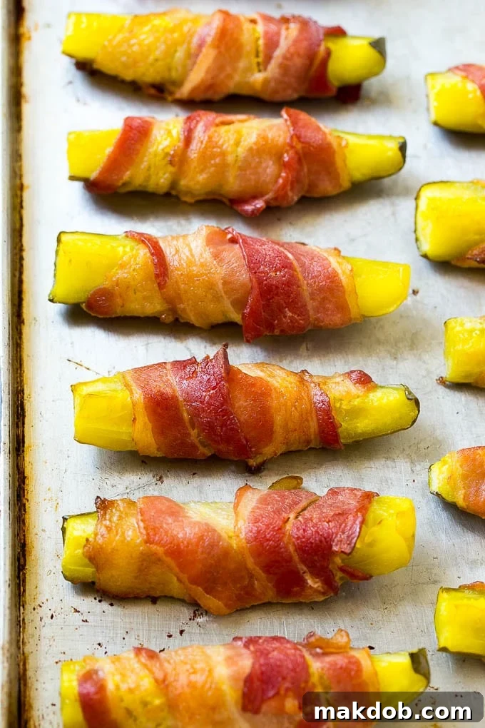 Crispy bacon wrapped pickle spears on a sheet pan.