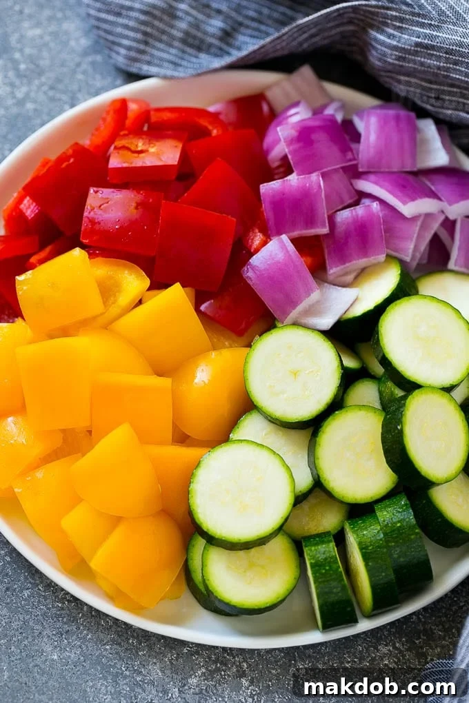 Freshly chopped zucchini, red peppers, yellow peppers, and red onion, perfectly prepped for making delicious grilled chicken skewers.