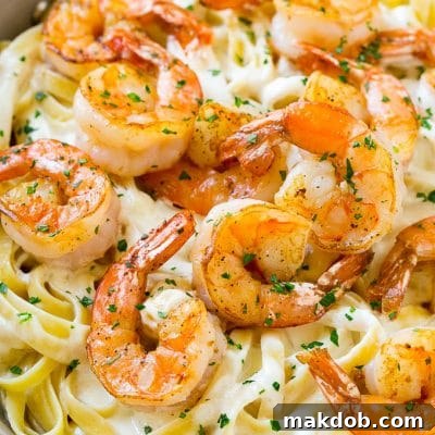 Shrimp alfredo in a skillet, topped with chopped parsley.