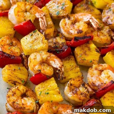 Skewers of jerk shrimp and pineapple, topped with parsley.