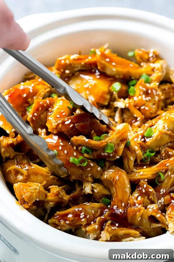 Effortless Slow Cooker Teriyaki Chicken 4 A slow cooker full of teriyaki chicken with tongs in it.