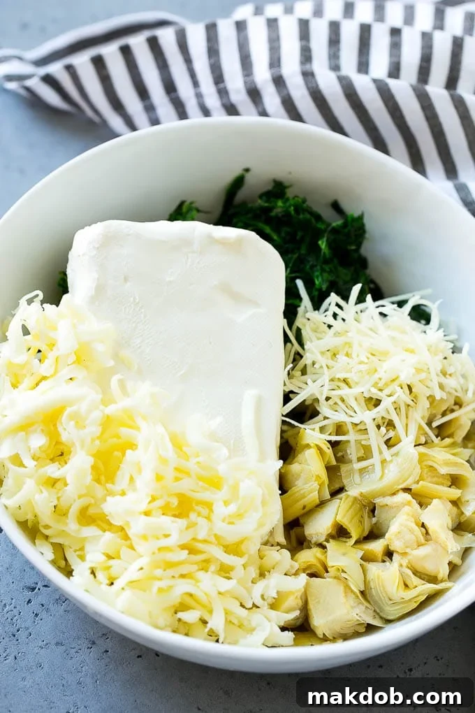 A bowl filled with a creamy mixture of cream cheese, fresh spinach, artichoke hearts, and shredded cheese, ready for wonton filling.
