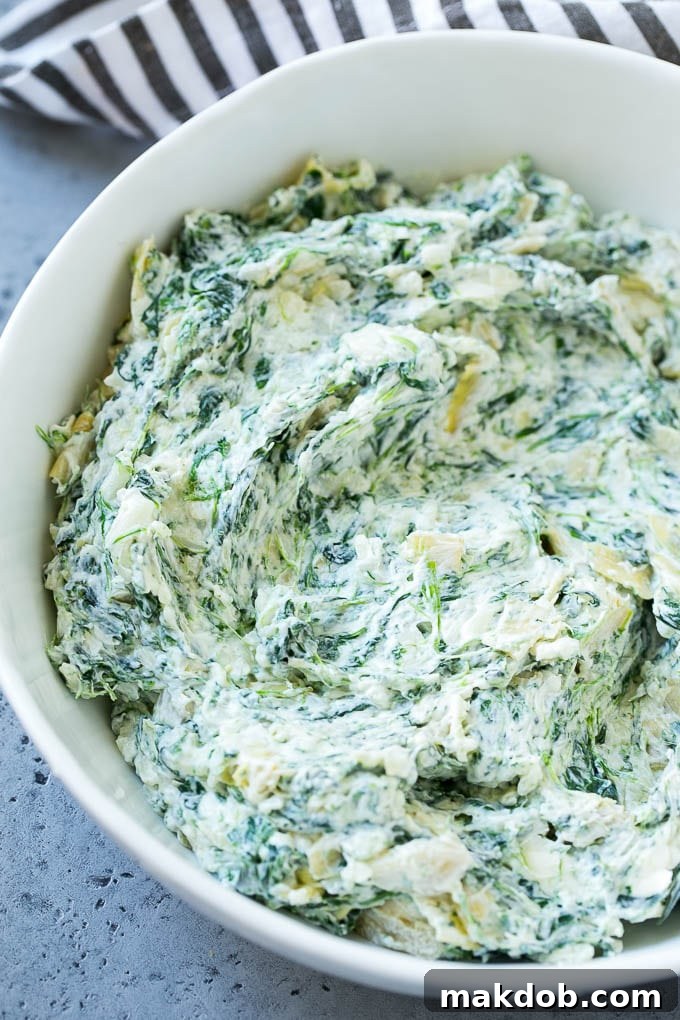 A bowl of the creamy spinach artichoke dip filling mixture.