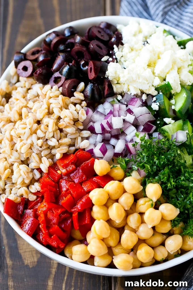 Farro Salad Recipe | Healthy Salad #salad #healthy #cleaneating #farro #dinner #dinneratthezoo Cooked farro, roasted peppers, chickpeas, herbs, and olives in a bowl.