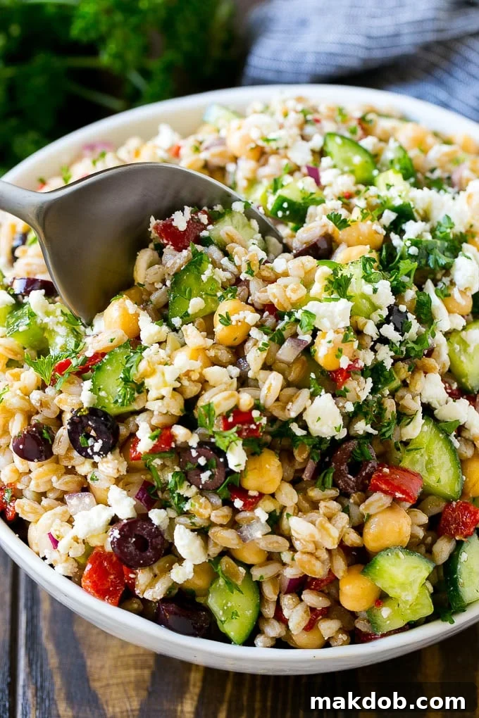 Farro Salad Recipe | Healthy Salad #salad #healthy #cleaneating #farro #dinner #dinneratthezoo A bowl of farro salad with a serving spoon in it.