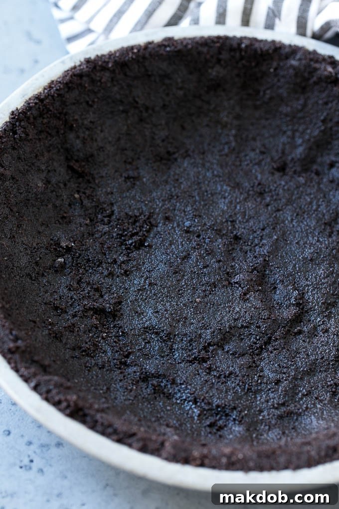 A perfectly formed chocolate cookie crust cooling in a metal pie dish, ready for its creamy filling.