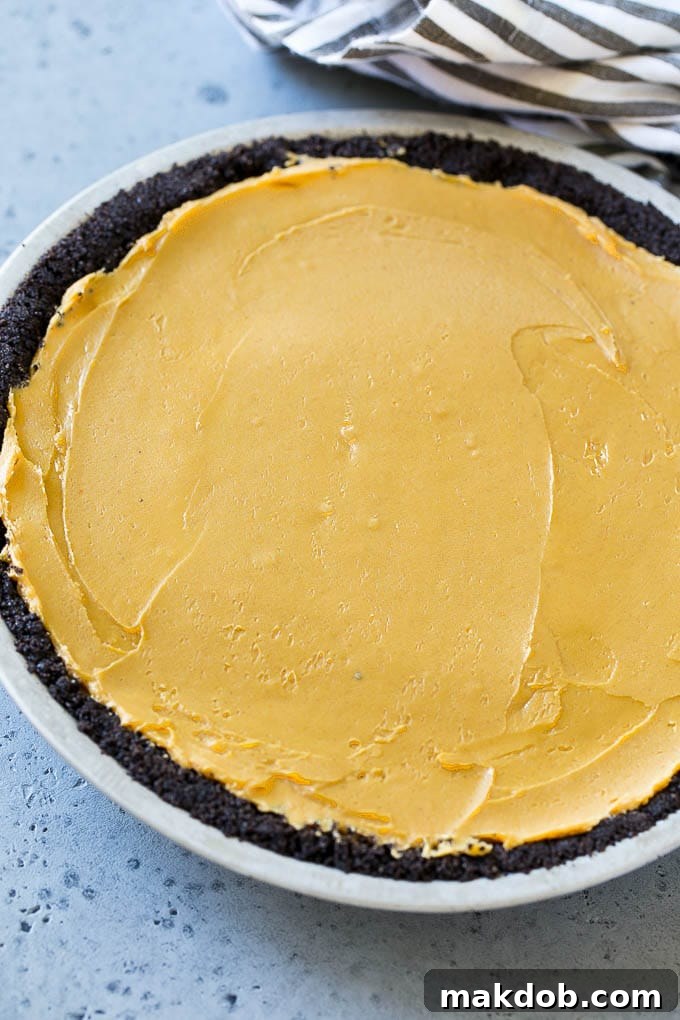 The rich, creamy peanut butter filling spread smoothly inside a dark chocolate cookie crust, ready for its final topping.