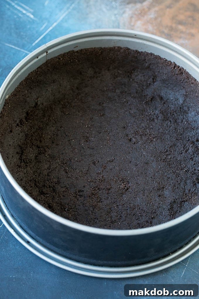 Ultimate No-Bake Oreo Cheesecake 3 A close-up view of an Oreo cookie crust neatly pressed into a springform pan, ready for the cheesecake filling.