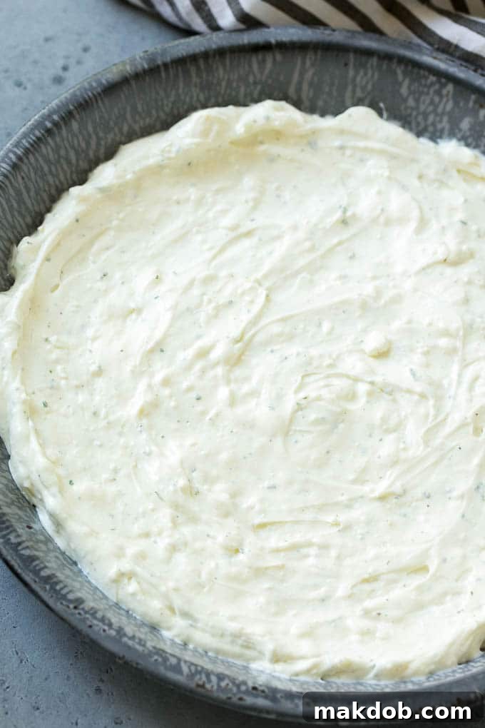 The Ultimate BLT Dip 3 A smooth layer of cream cheese and sour cream mixed with ranch seasoning, ready for toppings.