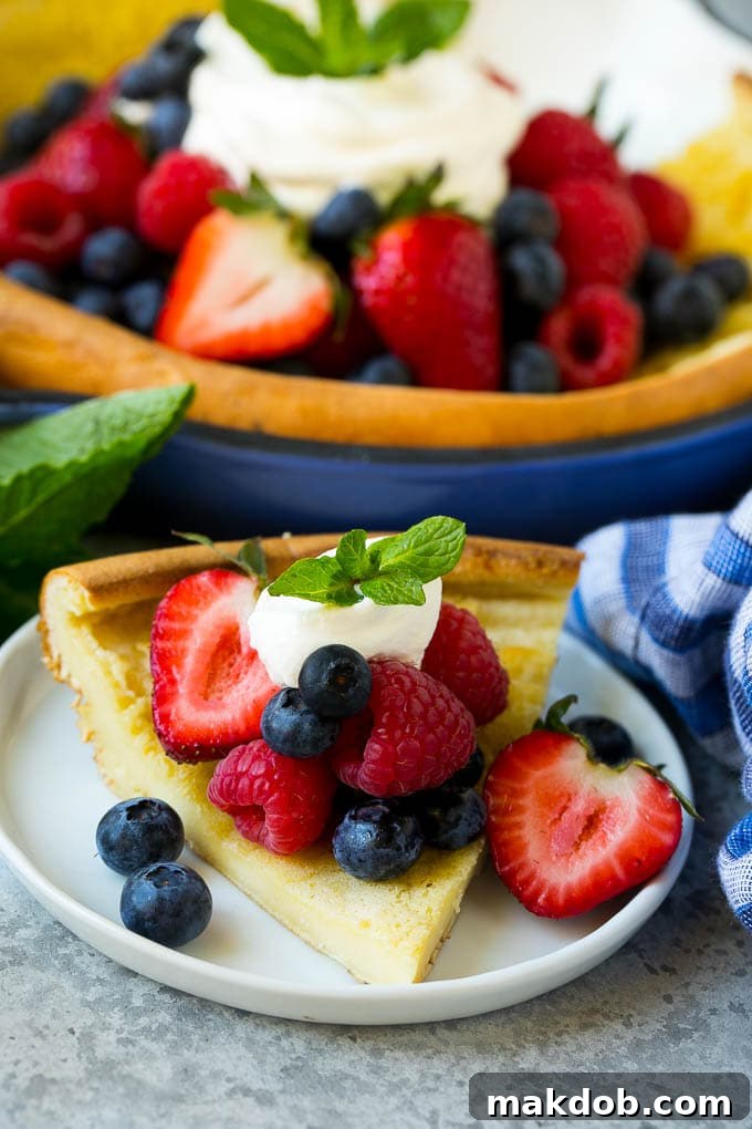 A slice of Dutch baby pancake topped with berries and whipped cream.