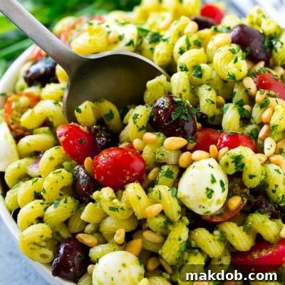 Pesto pasta salad with cherry tomatoes, olives, mozzarella balls, pine nuts and red onion.