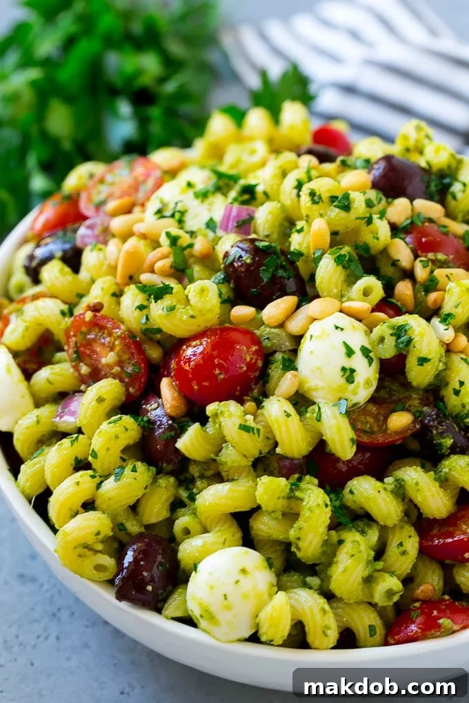 A delicious pesto pasta salad featuring corkscrew pasta, halved cherry tomatoes, Kalamata olives, and fresh mozzarella pearls, perfectly dressed and ready to serve.