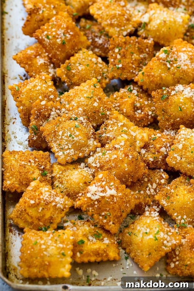 A sheet pan full of fried ravioli topped with parmesan cheese.