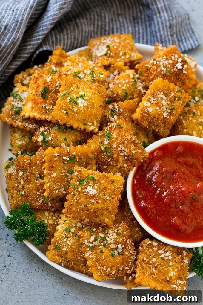 A plate of toasted ravioli with a side of marinara sauce for dipping.