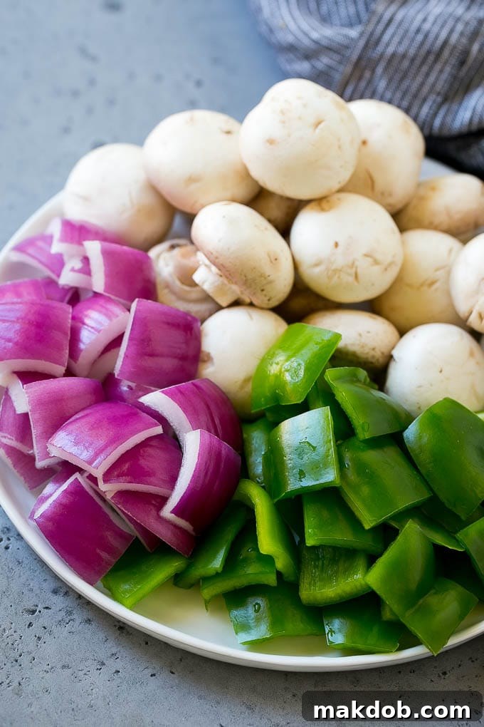 A plate of mushrooms, cut up bell peppers and red onion pieces.