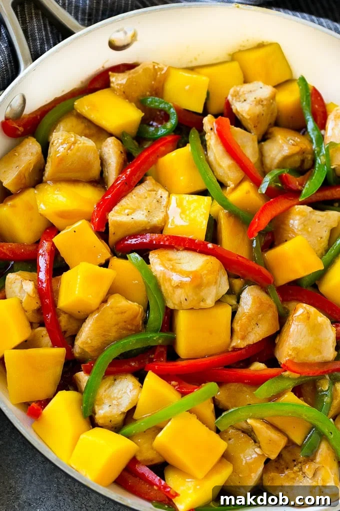 Mango chicken in a pan with red and green peppers.