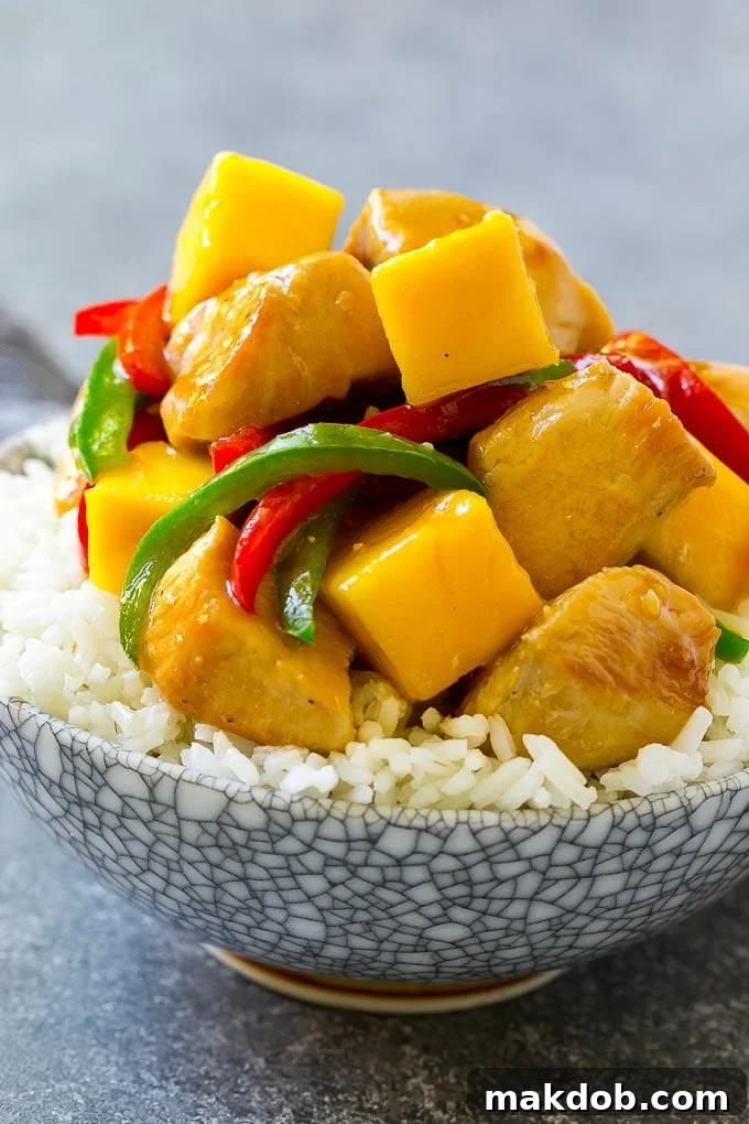 A bowl of mango chicken served over rice.
