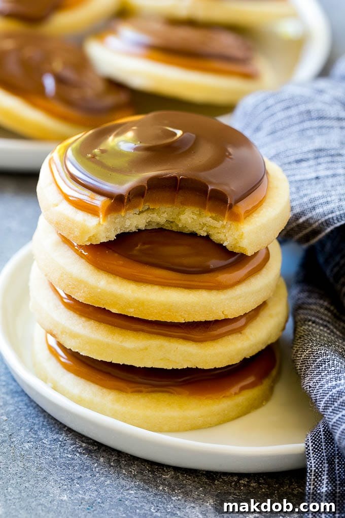 A stack of Twix cookies with a bite taken out of one, showcasing the shortbread, caramel, and chocolate layers.