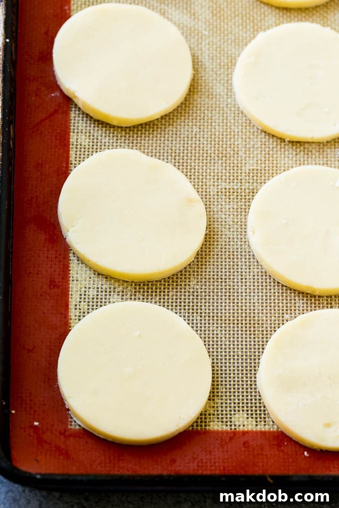Shortbread cookie dough rolled out on a baking sheet, ready to be cut into rounds.