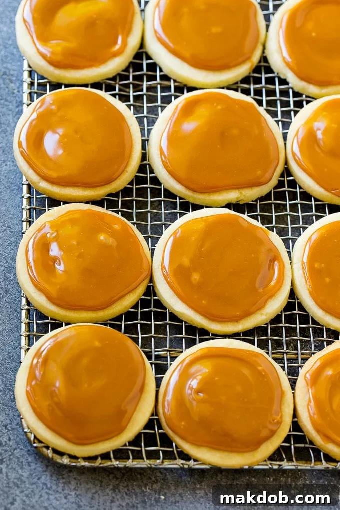Baked shortbread cookies topped with a golden caramel layer, cooling on a rack.