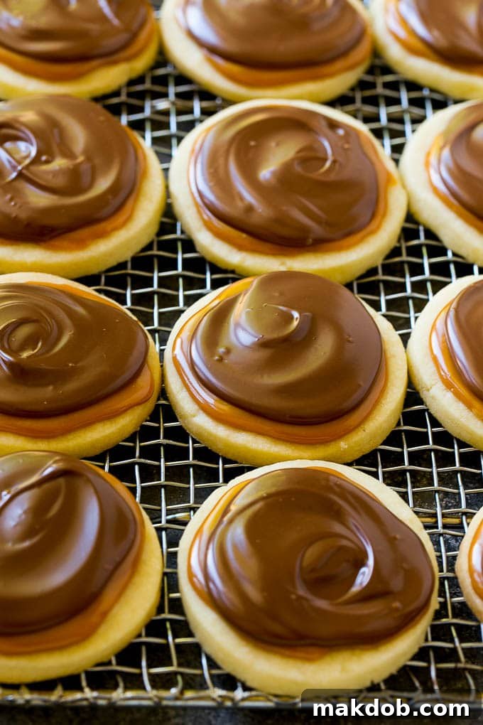Finished Twix cookies with chocolate and caramel layers, arranged on a cooling rack.