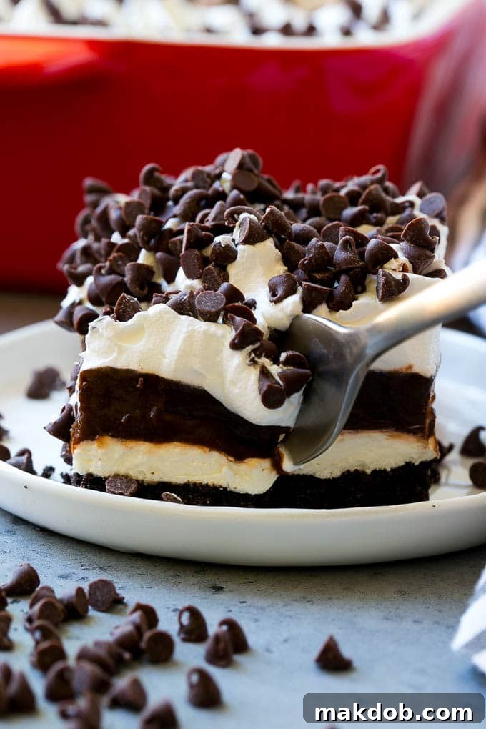A close-up shot of a single slice of chocolate lasagna, showing its perfectly defined layers, with a fork gently dug into the dessert, highlighting its creamy texture.
