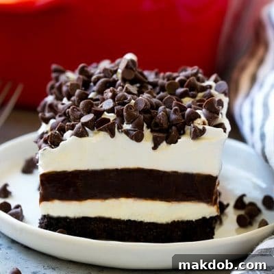 A slice of chocolate lasagna with layers of cookie crust, cheesecake and chocolate pudding.
