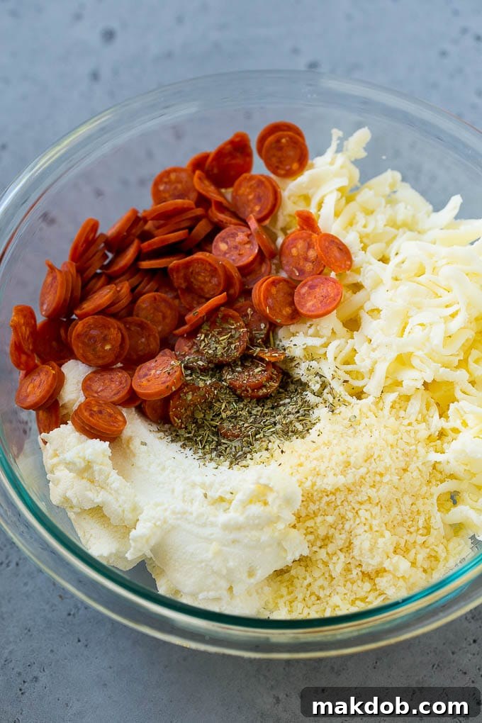 Ingredients for the cheesy pepperoni filling A bowl of creamy ricotta cheese, shredded mozzarella and parmesan, mini pepperoni, and Italian seasoning, prepared for the filling.