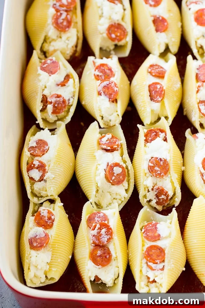 Stuffed pasta shells in tomato sauce Cooked pasta shells filled with a rich ricotta cheese mixture, nestled in a baking dish with tomato sauce at the bottom.