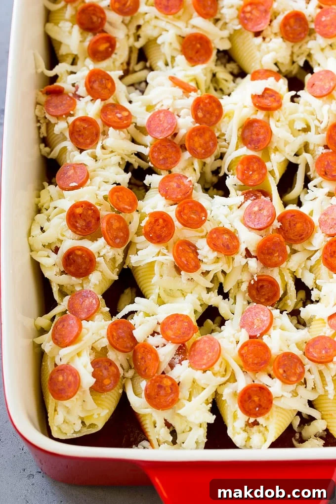 Pizza Stuffed Shells | Stuffed Shells Recipe | Italian Stuffed Shells #pizza #pasta #cheese #pepperoni #dinner #dinneratthezoo Pasta shells topped with mini pepperoni and shredded cheese in a baking dish.