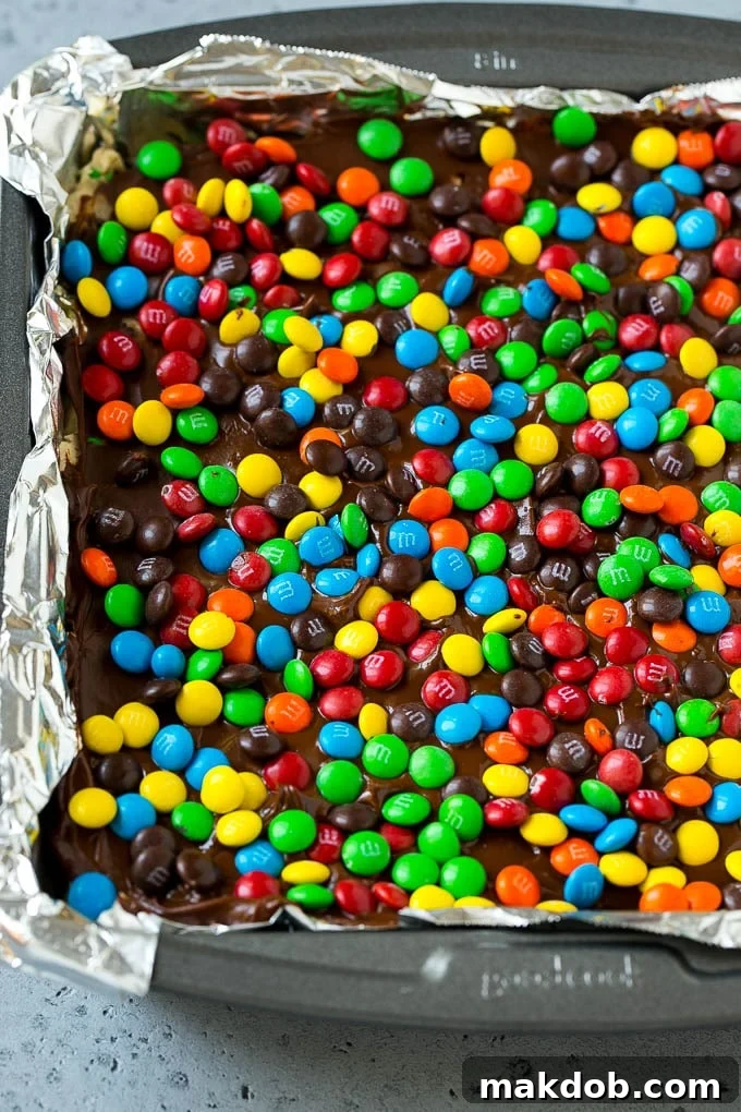 A pan of cookie dough bars topped with chocolate and miniature M&M's.