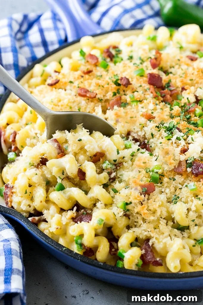 A skillet of jalapeno popper mac and cheese topped with crispy breadcrumbs, cilantro and bacon.
