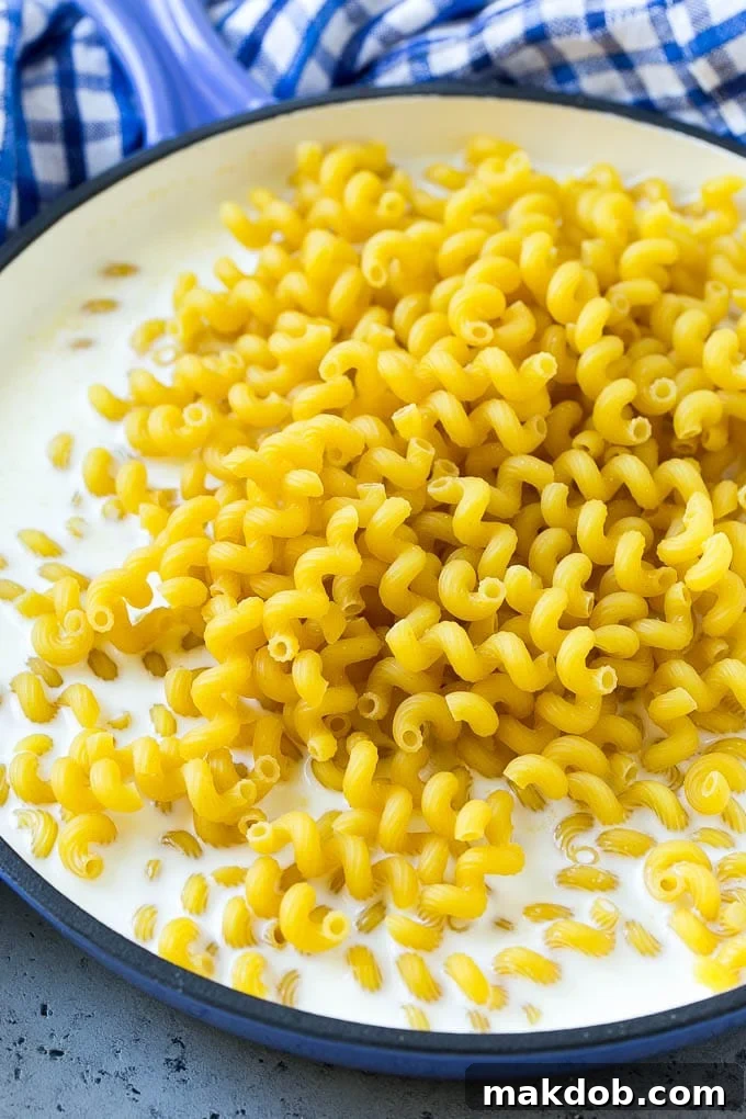Pasta in milk with seasonings in a pan.