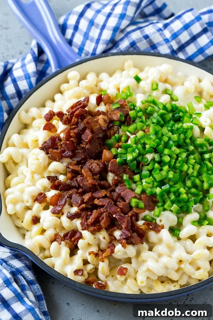 Macaroni and cheese in a skillet topped with bacon and diced jalapenos.