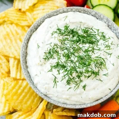Creamy Dill Delight 7 A bowl of creamy dill dip surrounded by potato chips and vegetables.