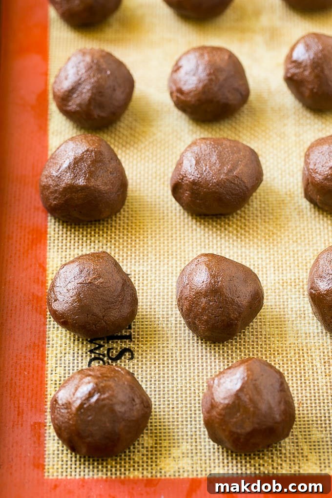 Chocolate Cookie Dough for Nutella Stuffed Cookies Balls of rich chocolate cookie dough ready to be stuffed with Nutella on a parchment-lined baking sheet.