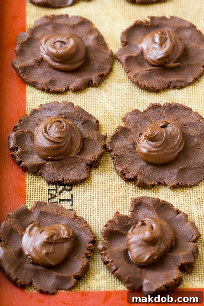 Preparing Nutella Stuffed Cookies Cookie dough discs with dollops of frozen Nutella in the center, ready to be folded and baked.