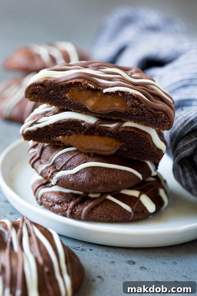 Gooey Nutella Stuffed Cookies A stack of Nutella stuffed chocolate cookies on a plate, with one cookie pulled apart to show the melted Nutella filling.