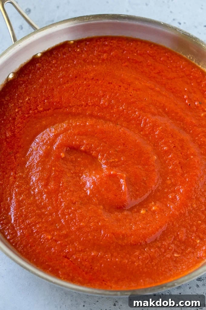 Rich tomato puree, melted butter, and fragrant garlic simmering together in a skillet, forming the base of the creamy vodka sauce.