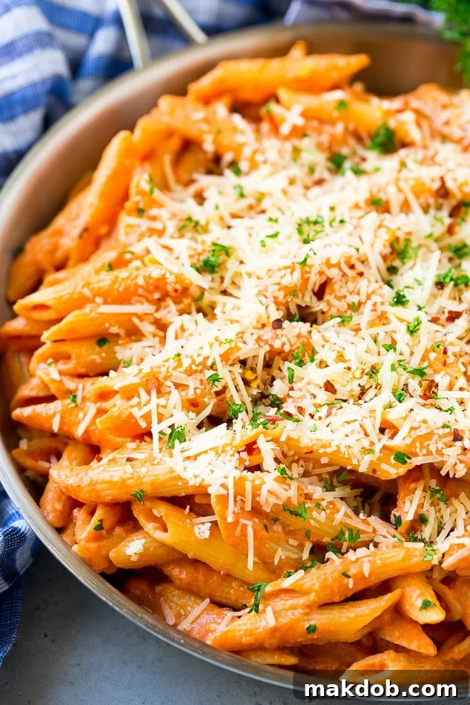 A skillet of penne alla vodka topped with shredded parmesan cheese.
