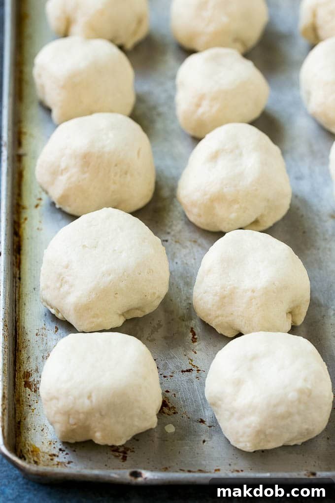A close-up view of biscuit dough expertly wrapped around a cube of cheddar cheese, with the seams tightly pinched to seal, ready for baking.