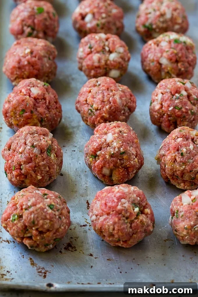 Classic Italian Slow Cooker Meatballs 4 Raw meatballs on a baking sheet.