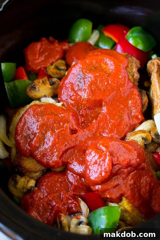 Slow Cooker Chicken Cacciatore Recipe | Italian Chicken #chicken #crockpot #slowcooker #dinner #italianfood #peppers #dinneratthezoo Marinara sauce poured over chicken and vegetables.