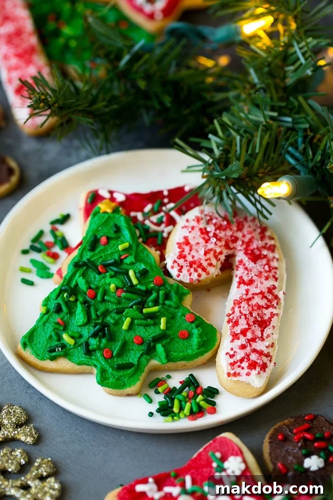 Christmas Sugar Cookies Recipe | Christmas Cookies #cookies #frosting #sprinkles #sugarcookies #christmas #dessert #dinneratthezoo A beautiful selection of decorated Christmas sugar cookies presented on a white serving plate, with subtle holiday decorations in the background.