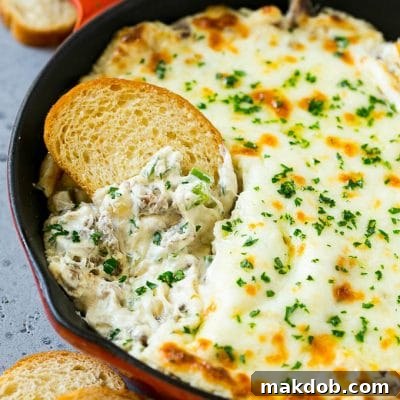 Loaded Philly Cheesesteak Dip 2 Philly cheesesteak dip with a baguette piece scooping some dip out.