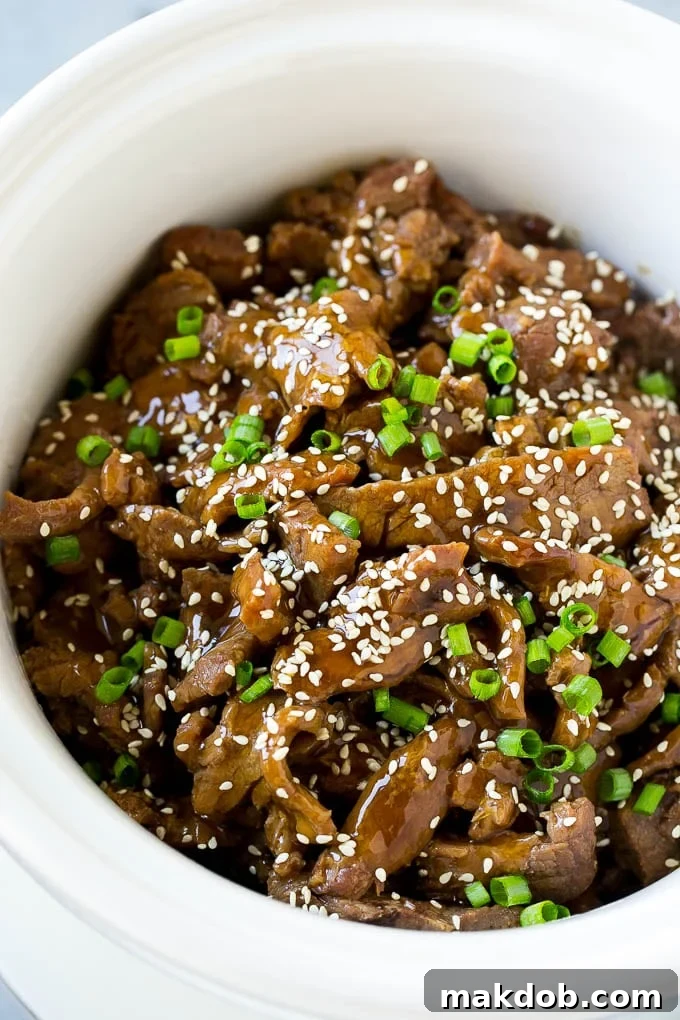 Slow cooker Korean beef featuring perfectly tender flank steak slices luxuriating in a sweet and savory sauce, all contained within a crock pot.