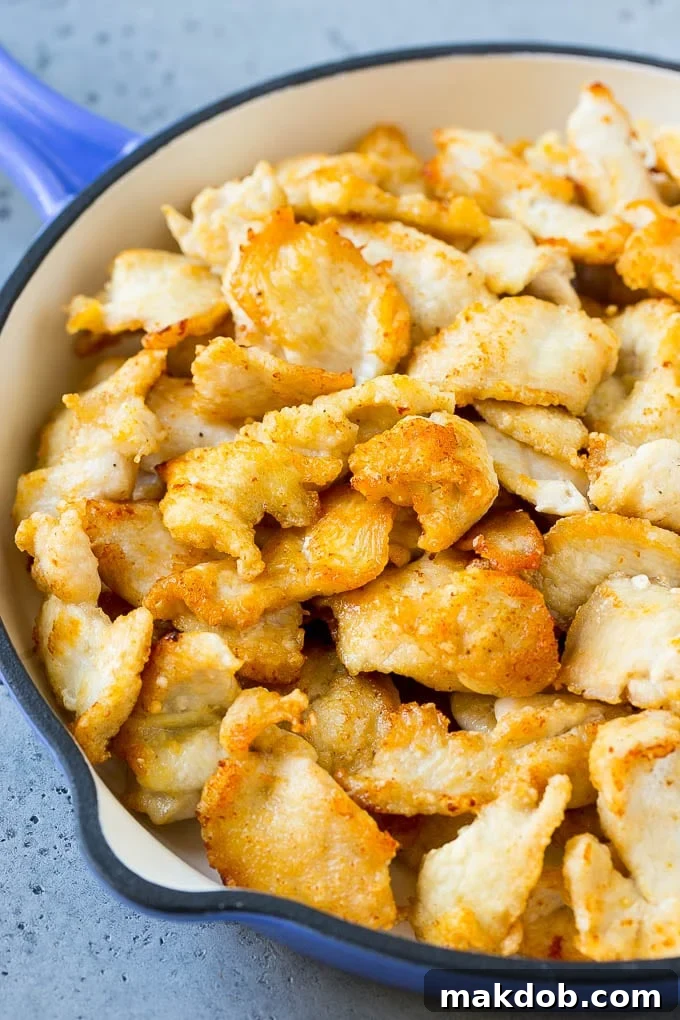 Crispy sliced chicken breast in a pan, ready to be coated in sauce.