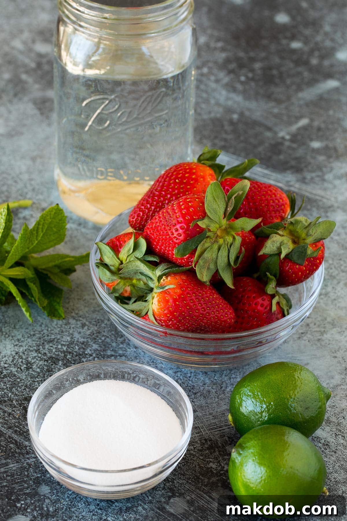 Luscious Strawberry Refresher 3 Fresh strawberries, sugar, limes, water, and mint arranged on a white surface, ready for making agua fresca.